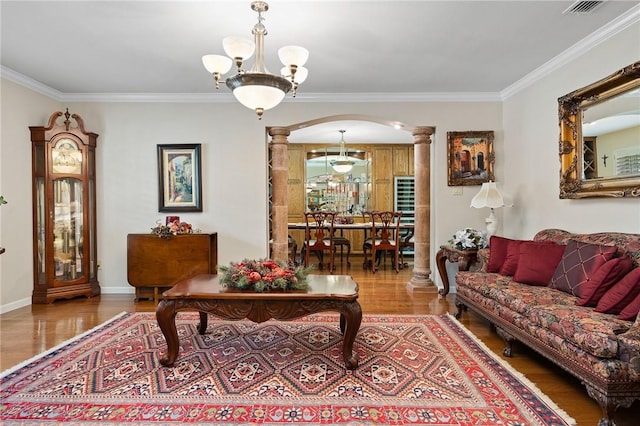 living area with ornate columns, a chandelier, wood finished floors, and arched walkways