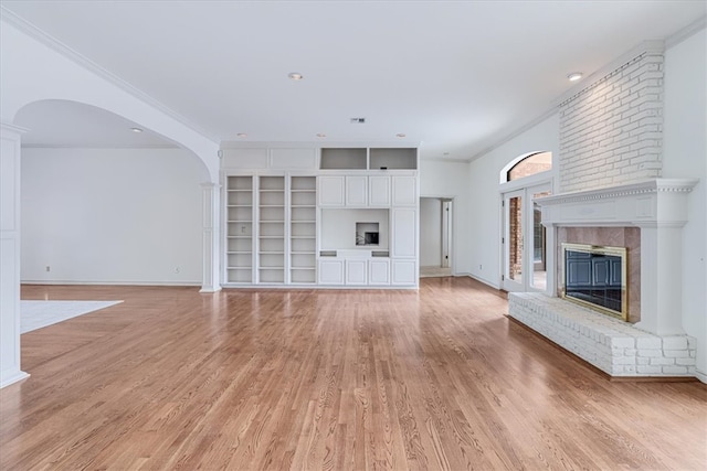 unfurnished living room with a brick fireplace, light hardwood / wood-style flooring, and ornamental molding