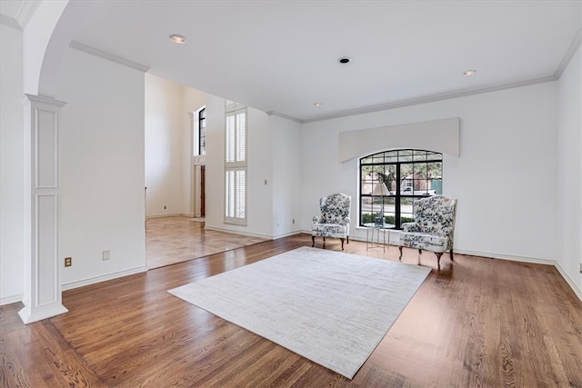 sitting room featuring hardwood / wood-style flooring, crown molding, and decorative columns