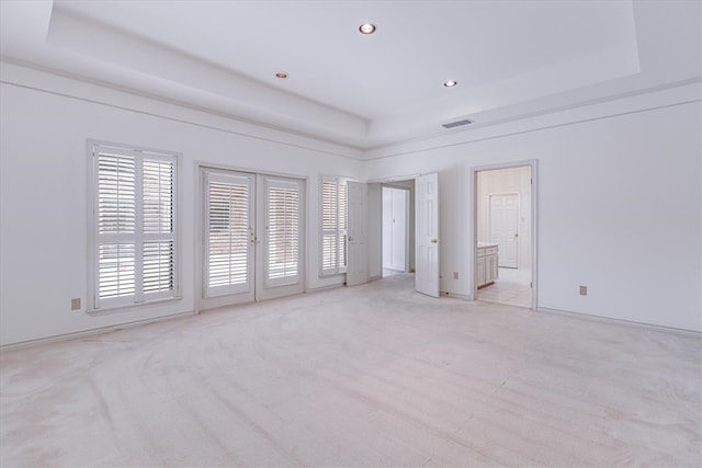 spare room with french doors, light carpet, and a raised ceiling