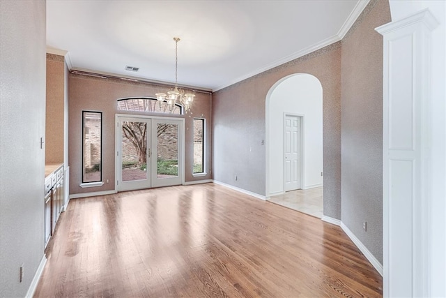 unfurnished room with ornamental molding, light hardwood / wood-style floors, and an inviting chandelier