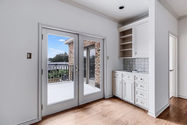 doorway to outside featuring sink, light hardwood / wood-style flooring, and crown molding