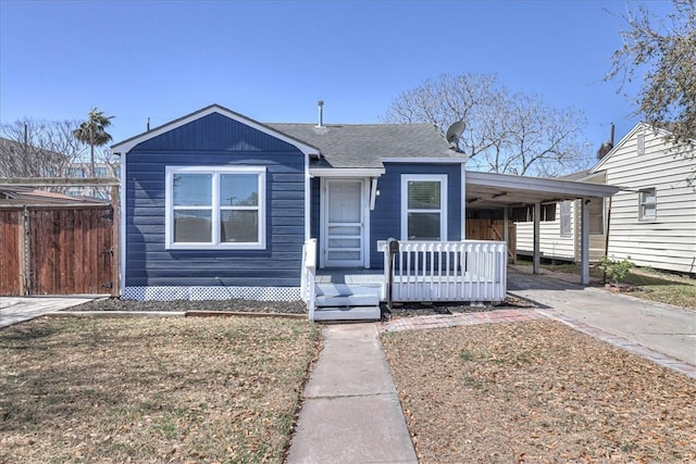 view of front of home featuring a carport, driveway, a shingled roof, and fence