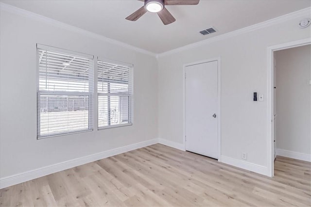 empty room with visible vents, light wood-style floors, baseboards, and ornamental molding