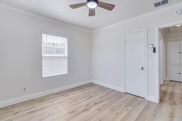 spare room with visible vents, light wood-style flooring, attic access, and ornamental molding