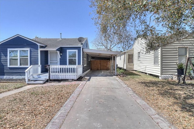 view of front of home with an attached carport, roof with shingles, and driveway