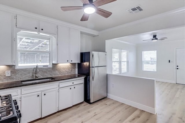 kitchen featuring gas stove, visible vents, freestanding refrigerator, ornamental molding, and a sink