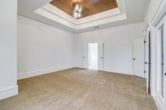 carpeted spare room with a raised ceiling and crown molding