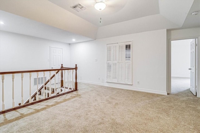 carpeted spare room with lofted ceiling and a raised ceiling