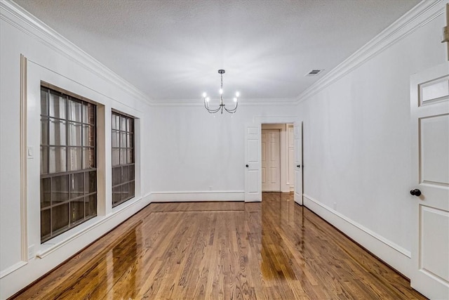 unfurnished dining area featuring wood-type flooring, ornamental molding, and a textured ceiling