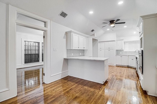 kitchen with hardwood / wood-style flooring, white cabinetry, tasteful backsplash, and kitchen peninsula