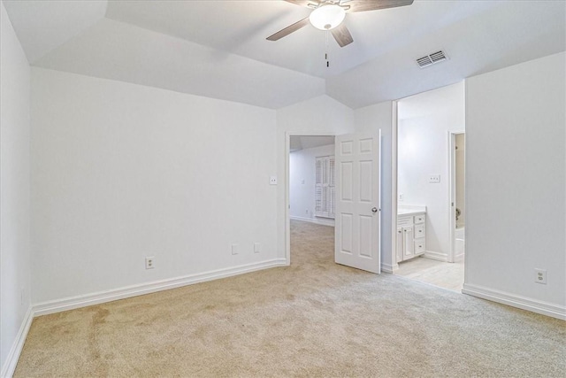 unfurnished bedroom featuring light carpet, ensuite bath, lofted ceiling, and ceiling fan