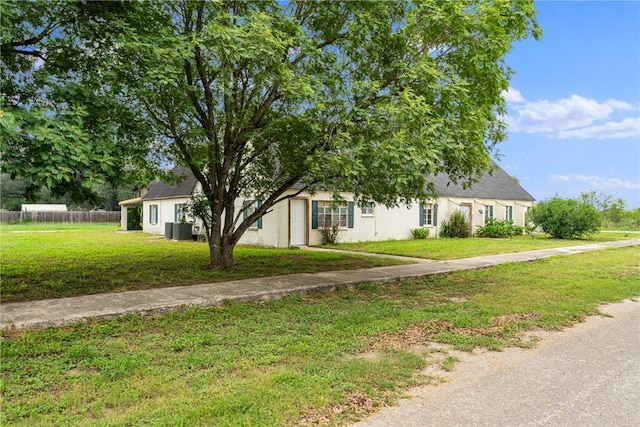 view of property hidden behind natural elements featuring cooling unit and a front lawn