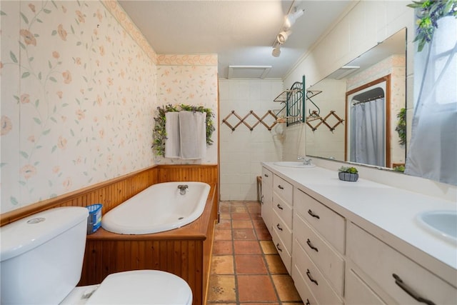 bathroom featuring a tub, track lighting, toilet, vanity, and ornamental molding