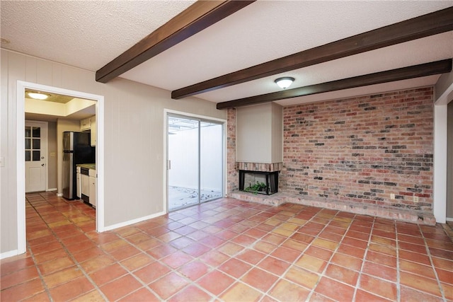 unfurnished living room with light tile patterned floors, beamed ceiling, a textured ceiling, and a brick fireplace