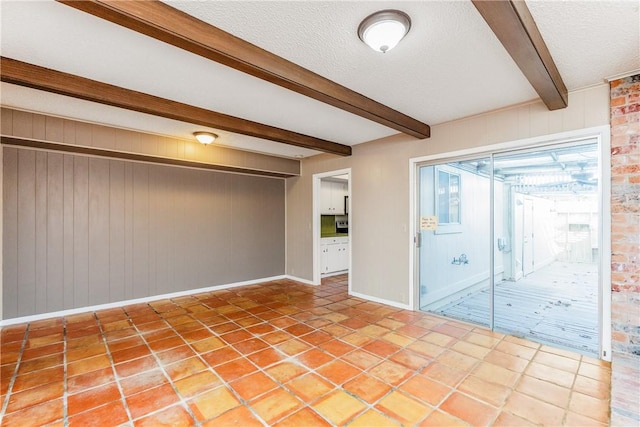 41 Townhouse, Corpus Christi, TX 78412 - spare room with beam ceiling, a textured ceiling, baseboards, wood walls, and light tile patterned floors
