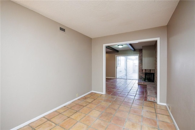 unfurnished room with beam ceiling, a fireplace, light tile patterned floors, and a textured ceiling