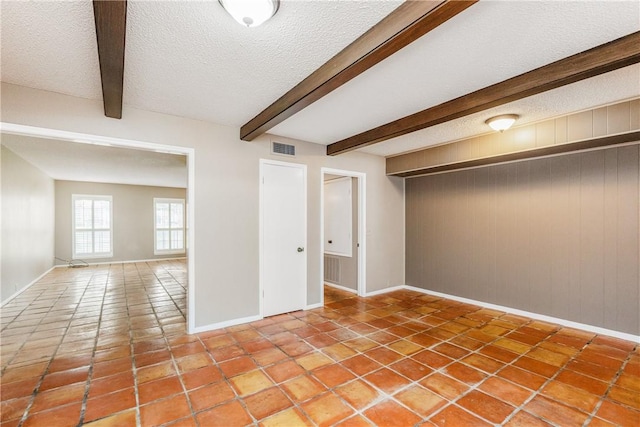 41 Townhouse, Corpus Christi, TX 78412 - tiled empty room with a textured ceiling, baseboards, beamed ceiling, and wood walls