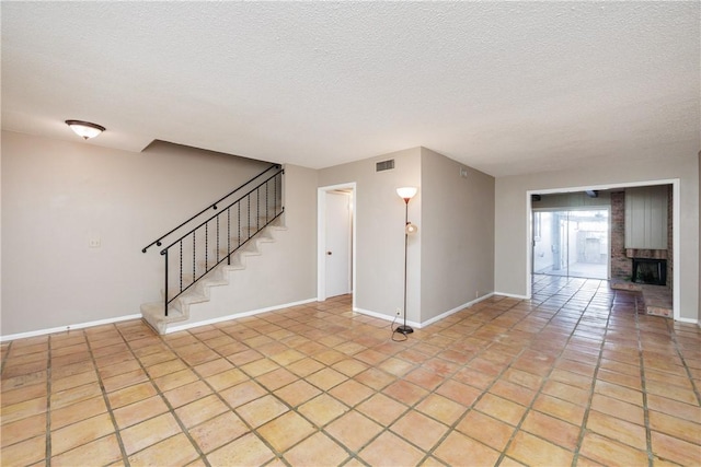 unfurnished room featuring light tile patterned floors, a textured ceiling, and a brick fireplace