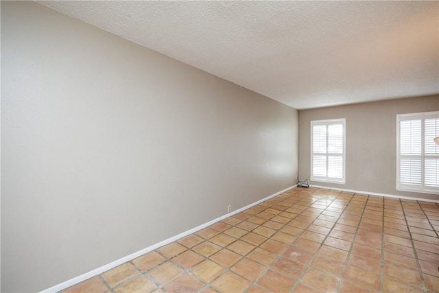 tiled spare room featuring a textured ceiling