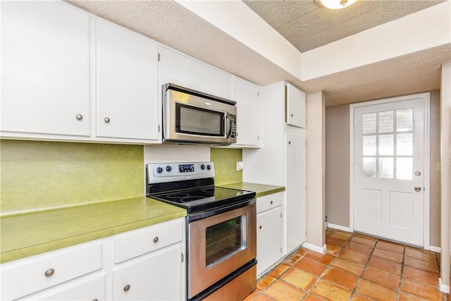 41 Townhouse, Corpus Christi, TX 78412 - kitchen with stainless steel appliances, white cabinets, baseboards, light countertops, and light tile patterned floors