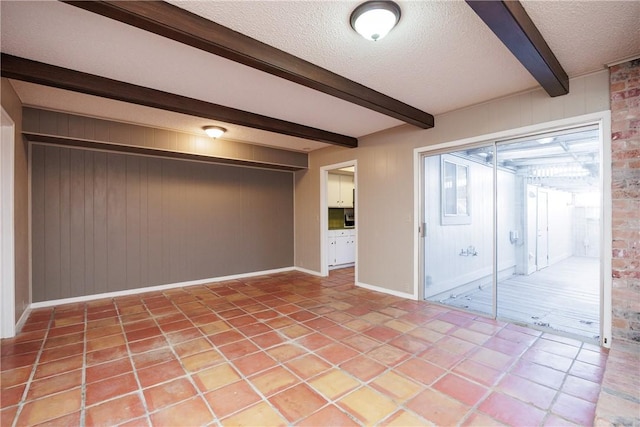 unfurnished room featuring beamed ceiling, a textured ceiling, and wooden walls