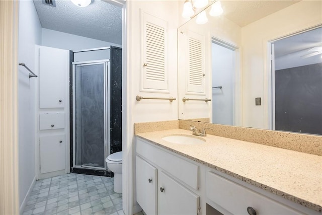 bathroom featuring a textured ceiling, vanity, toilet, and walk in shower