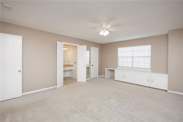 interior space with connected bathroom, light colored carpet, and ceiling fan