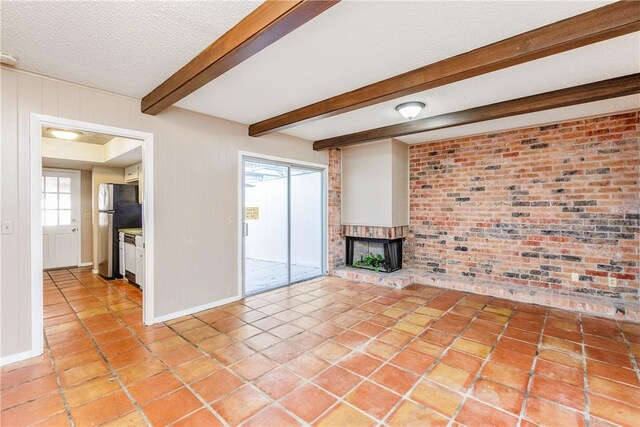 41 Townhouse, Corpus Christi, TX 78412 - unfurnished living room with a brick fireplace, a textured ceiling, light tile patterned flooring, beamed ceiling, and brick wall