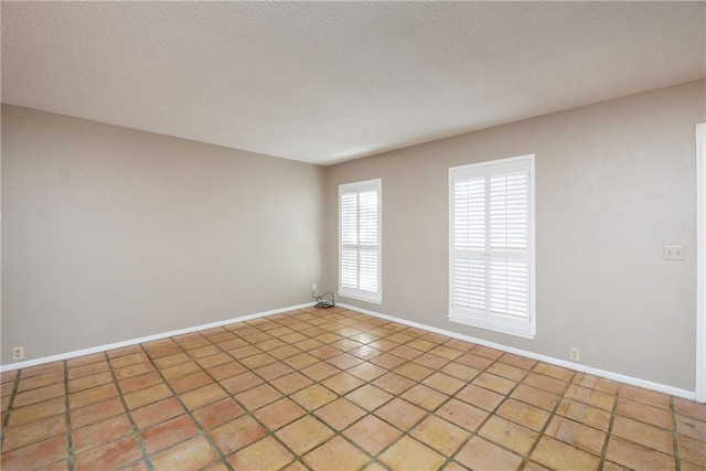 empty room with light tile patterned flooring and a textured ceiling