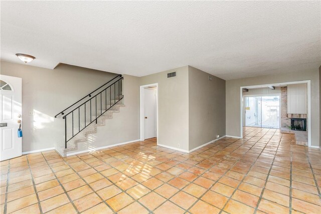 41 Townhouse, Corpus Christi, TX 78412 - foyer entrance with baseboards, stairs, a textured ceiling, a fireplace, and light tile patterned floors