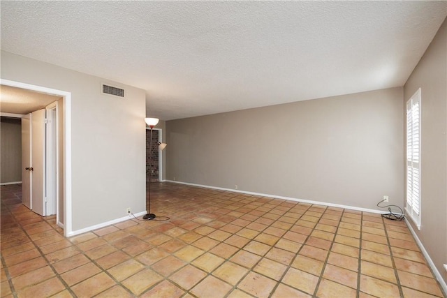 tiled spare room featuring a textured ceiling