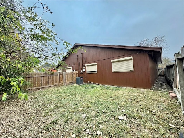 view of side of property with a lawn and central AC