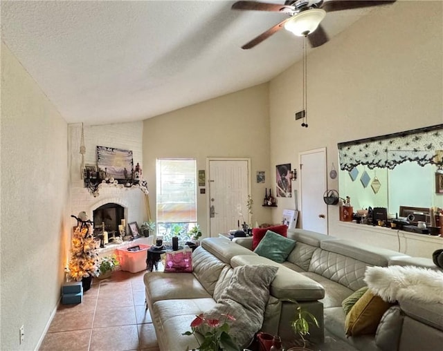 living room featuring a brick fireplace, a textured ceiling, ceiling fan, high vaulted ceiling, and light tile patterned flooring