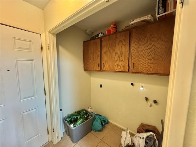 laundry room with hookup for an electric dryer, light tile patterned flooring, and cabinets