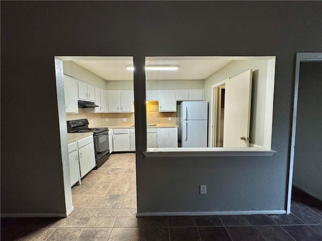 kitchen with electric range, white fridge, and white cabinetry