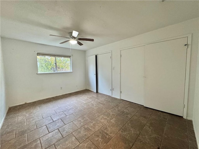 unfurnished bedroom with ceiling fan and two closets