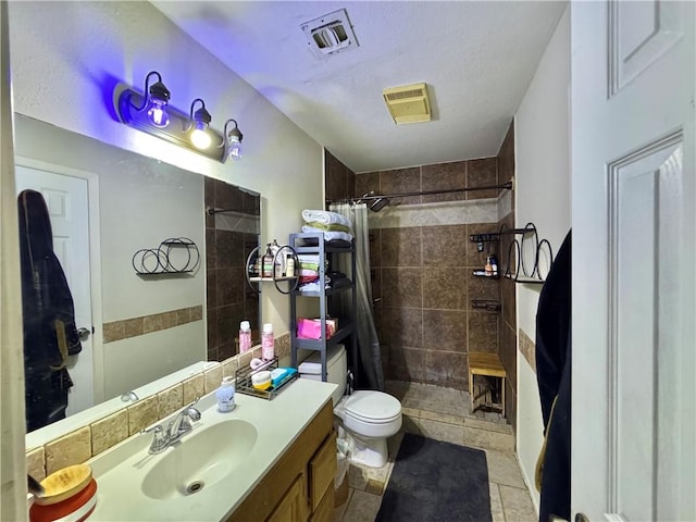 bathroom featuring a tile shower, vanity, toilet, and tile patterned floors