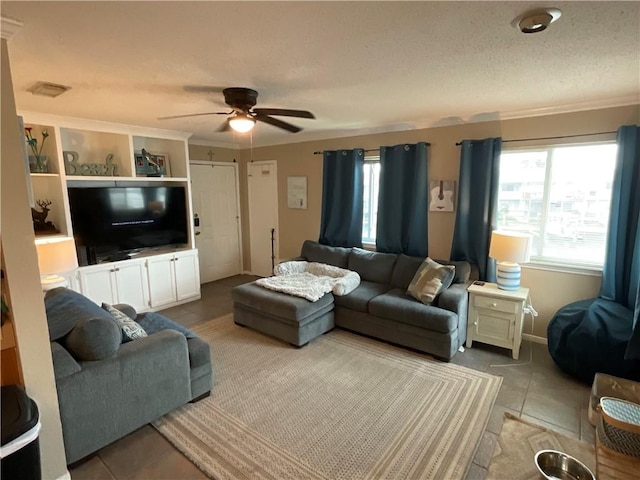 living area featuring ceiling fan, tile patterned floors, a textured ceiling, and crown molding
