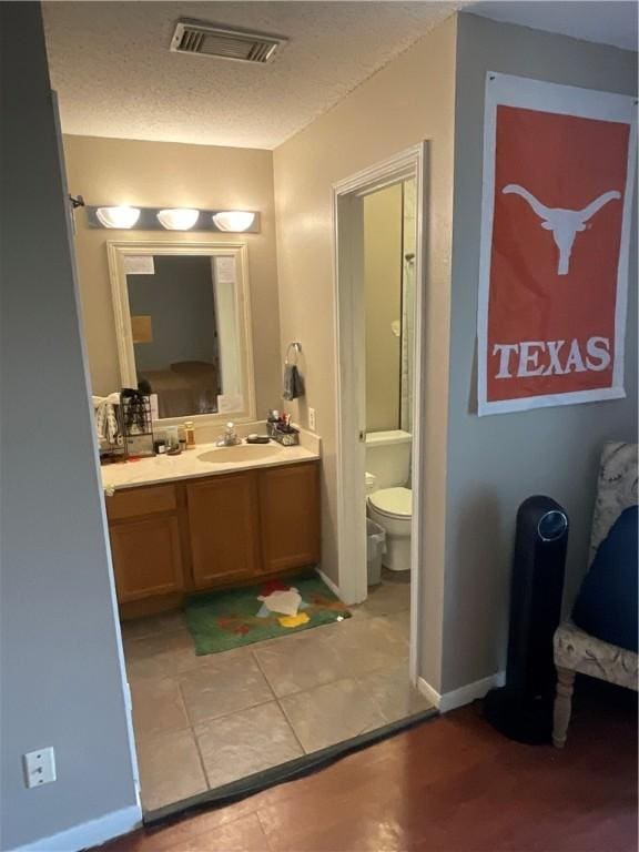 bathroom featuring vanity, toilet, baseboards, and a textured ceiling