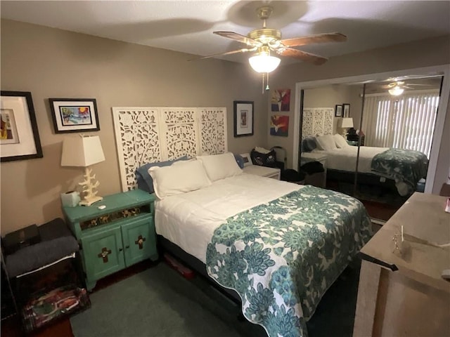 bedroom with a closet, ceiling fan, and dark carpet