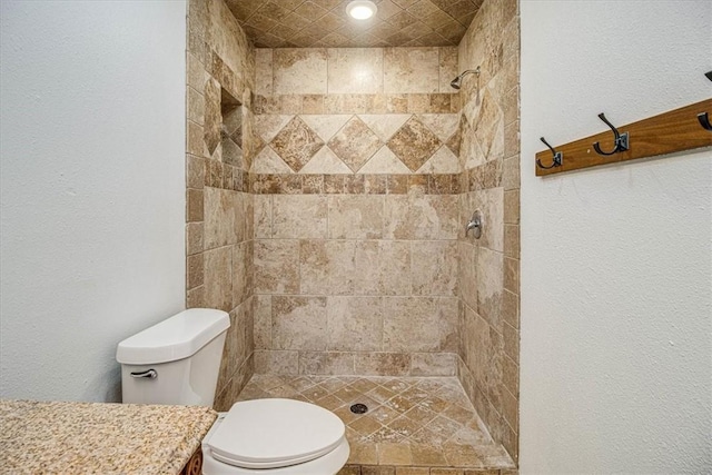 bathroom with vanity, tiled shower, and toilet