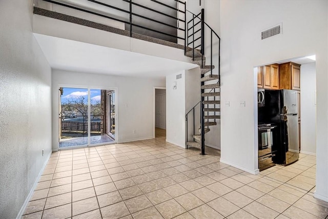 unfurnished living room featuring light tile patterned floors and a high ceiling