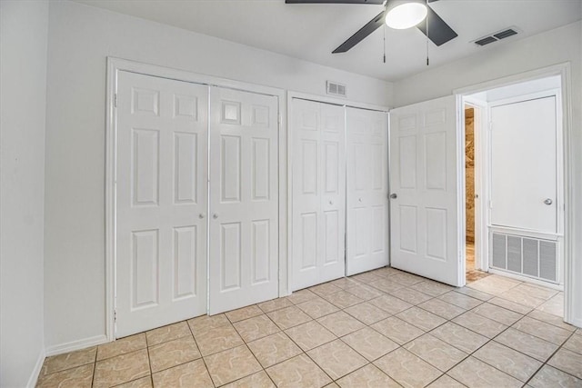 unfurnished bedroom featuring multiple closets, light tile patterned floors, and ceiling fan