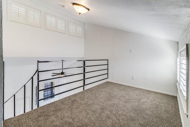 carpeted spare room featuring ceiling fan and a textured ceiling