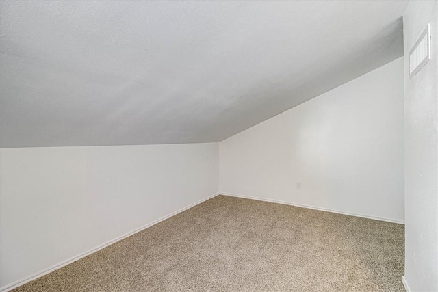 bonus room featuring lofted ceiling, carpet flooring, and a textured ceiling