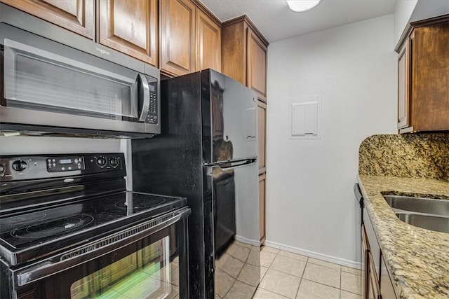 kitchen with tasteful backsplash, light tile patterned floors, light stone counters, and black / electric stove