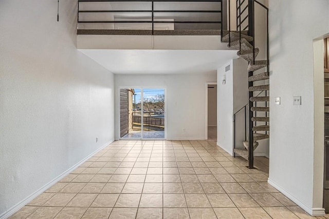 spare room featuring light tile patterned flooring and a high ceiling