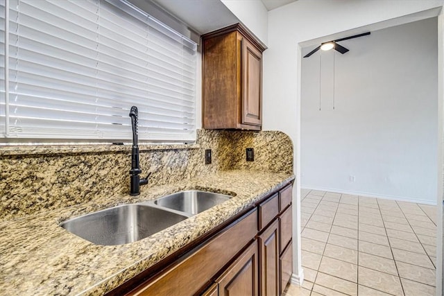 kitchen featuring sink, light tile patterned floors, light stone countertops, and ceiling fan