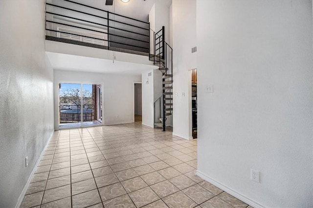 unfurnished room with ceiling fan, light tile patterned floors, and a high ceiling